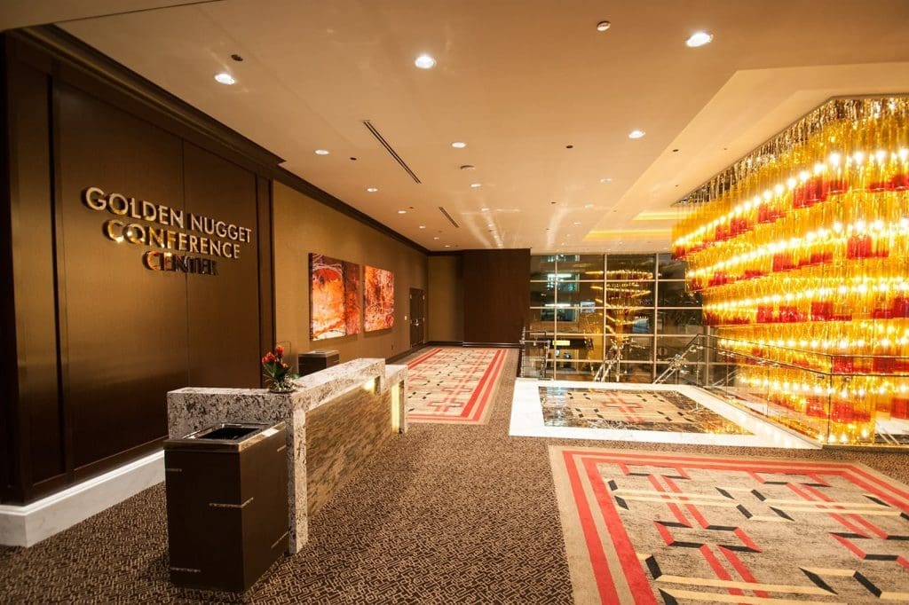 Golden Nugget Conference Center lobby with modern decor, red and beige carpets, abstract wall art, and a large illuminated yellow glass wall feature.